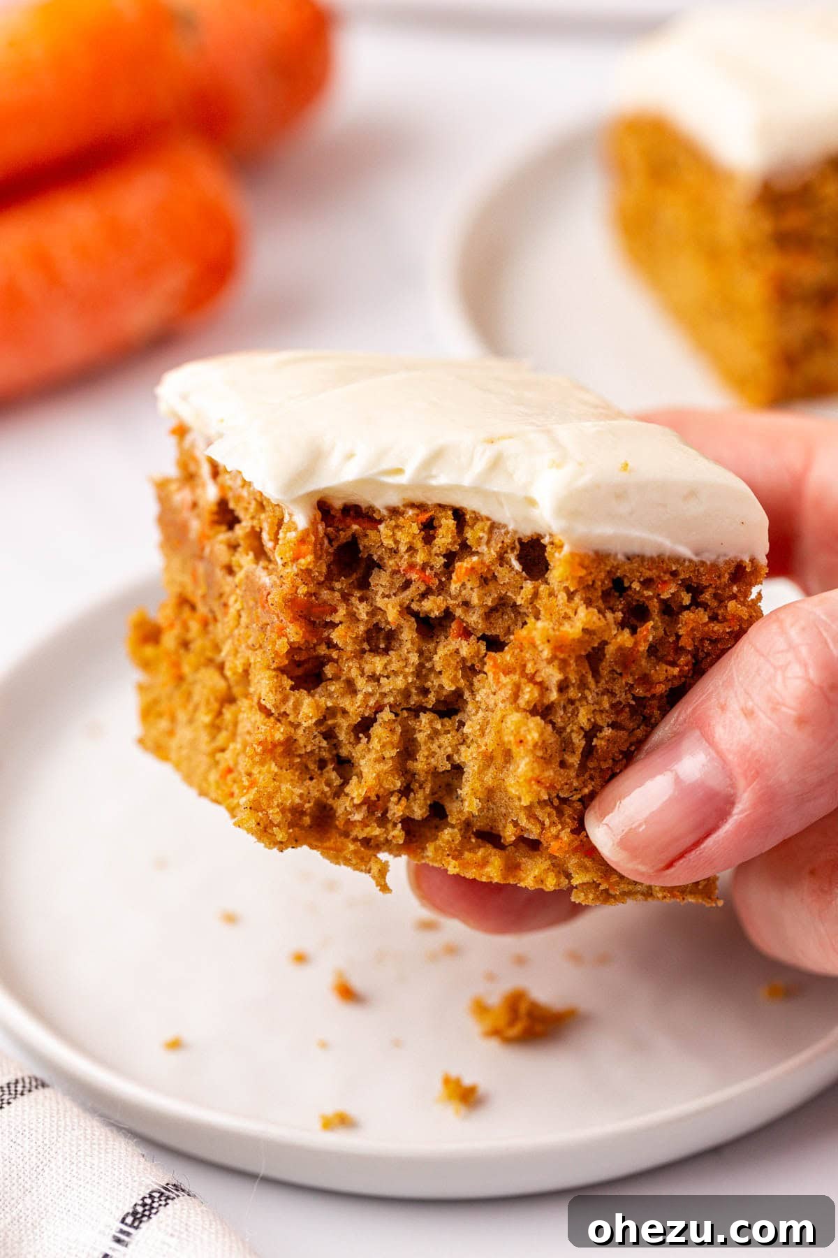 A stack of carrot cake snack bars presented on a white plate with a fork, ready to eat.