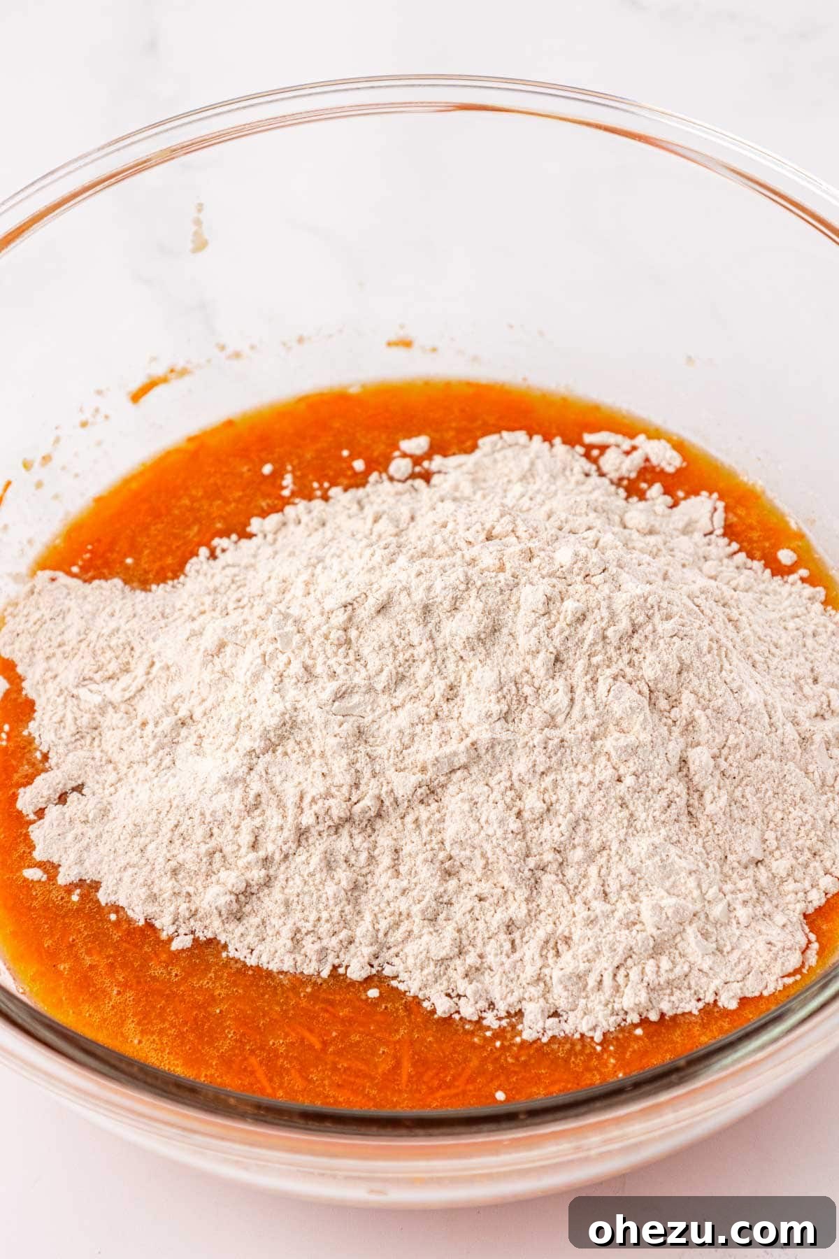 Pouring dry ingredients into the bowl of wet ingredients for carrot cake batter.