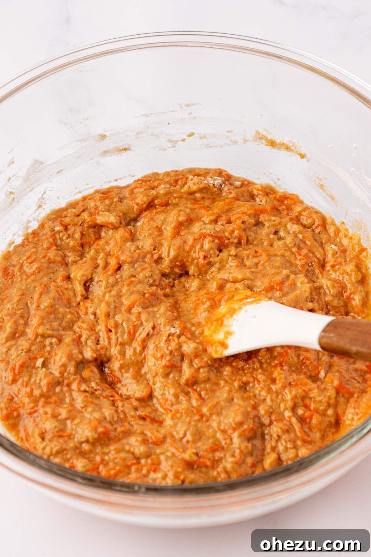Fully mixed carrot cake batter, showing grated carrots evenly distributed.