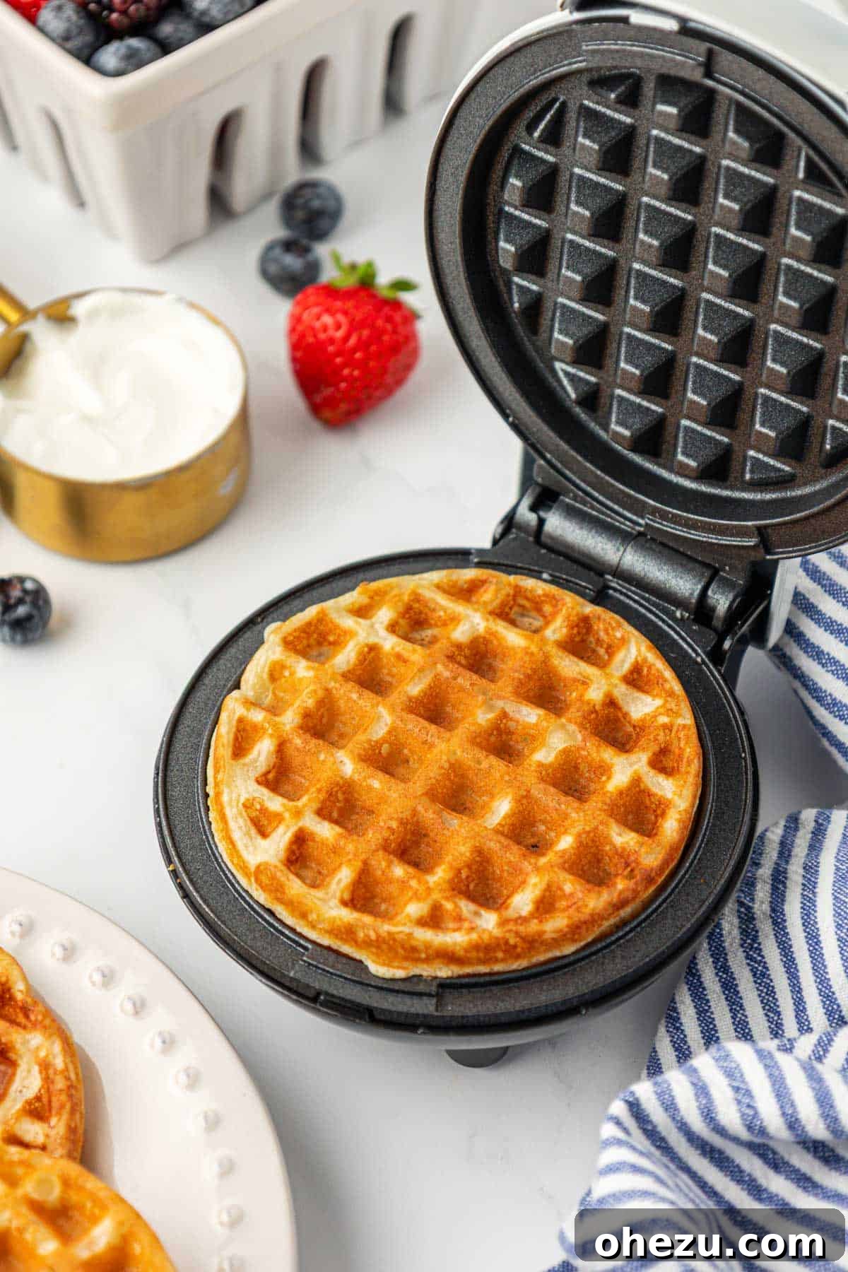 Protein-Packed Greek Yogurt Waffles 13 A Greek yogurt waffle cooking inside a mini waffle maker