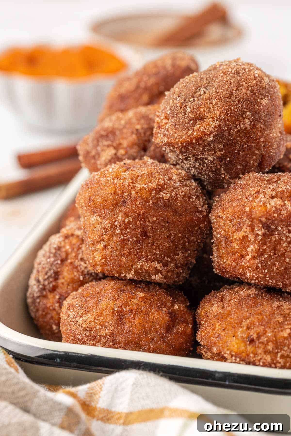 Spiced Pumpkin Donut Bites 19 A vibrant display of pumpkin donut mini muffins stacked high on a wooden cutting board