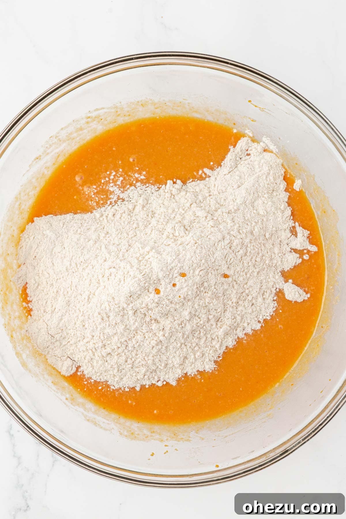 Spiced Pumpkin Donut Bites 9 Pouring dry ingredients into the bowl of wet ingredients for pumpkin muffins