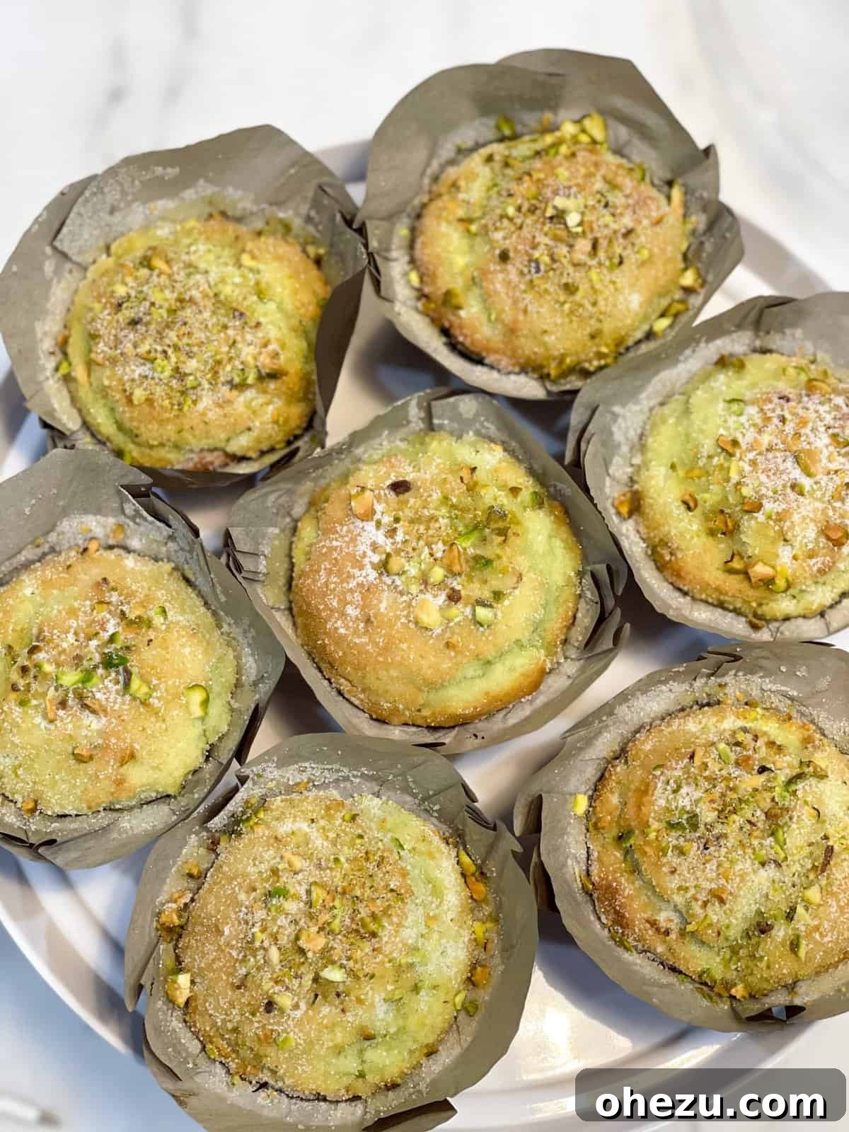 A close-up of a stack of bakery-style pistachio muffins showing their moist texture