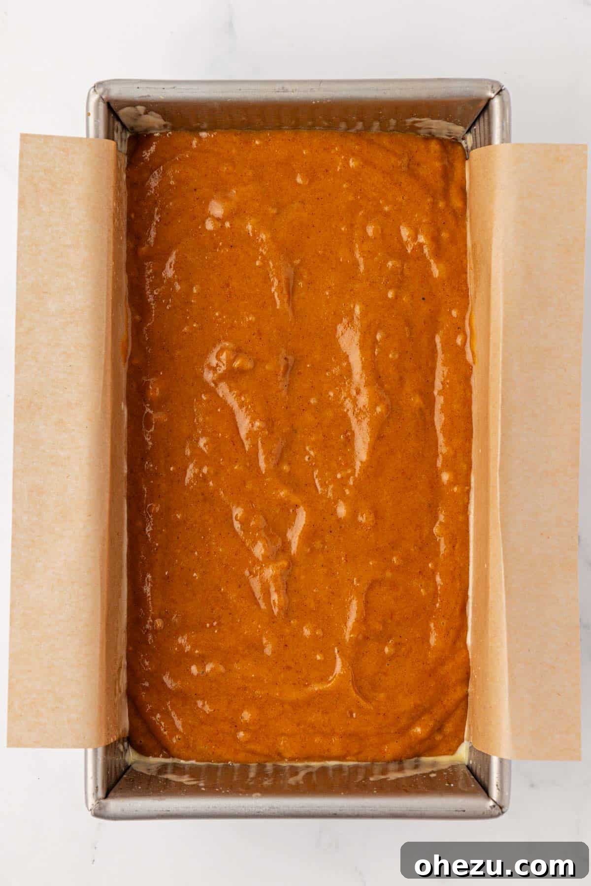 pumpkin bread batter being spread evenly into a greased loaf pan