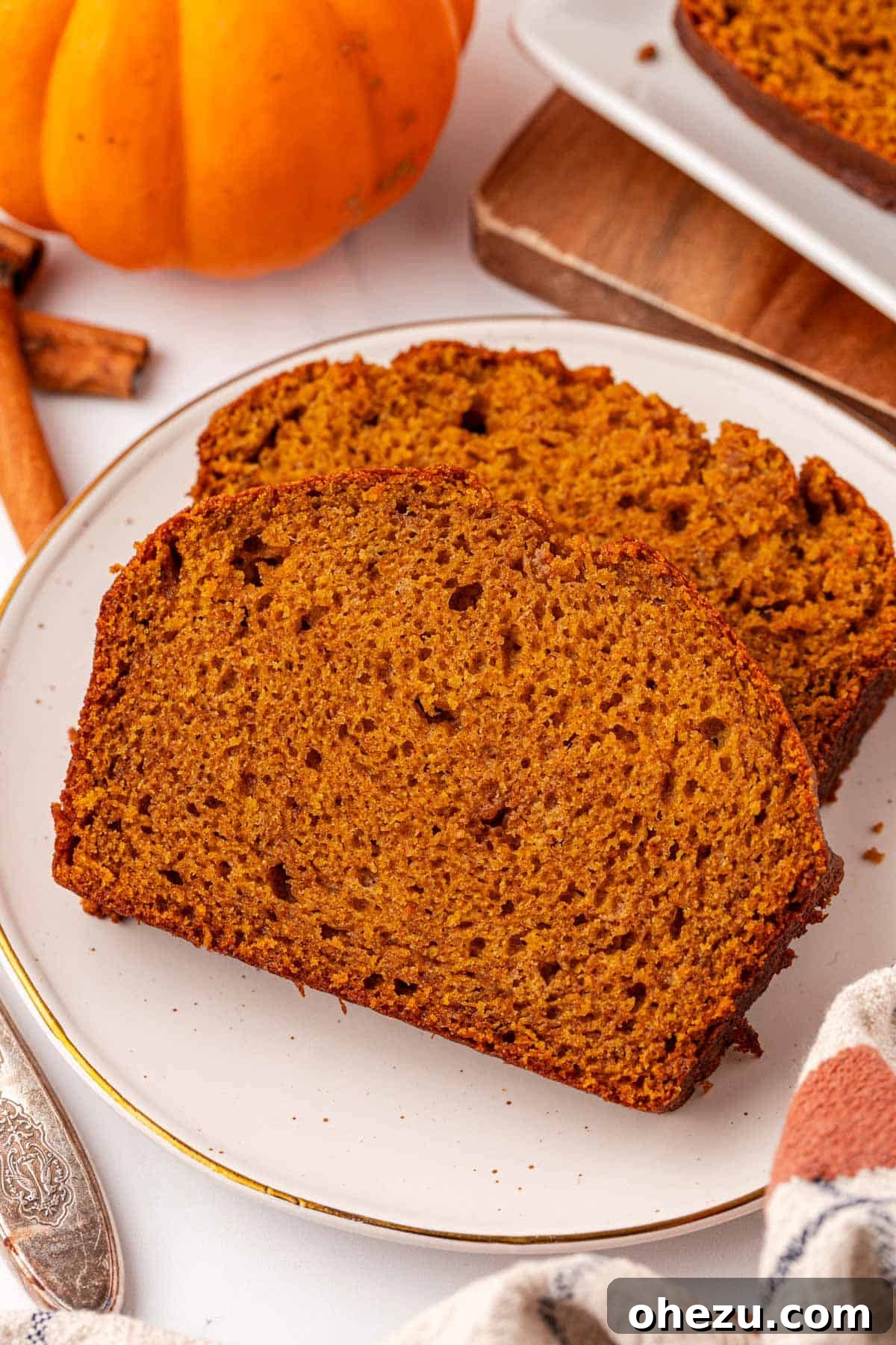 a thick slice of moist pumpkin bread on a cutting board, ready to eat