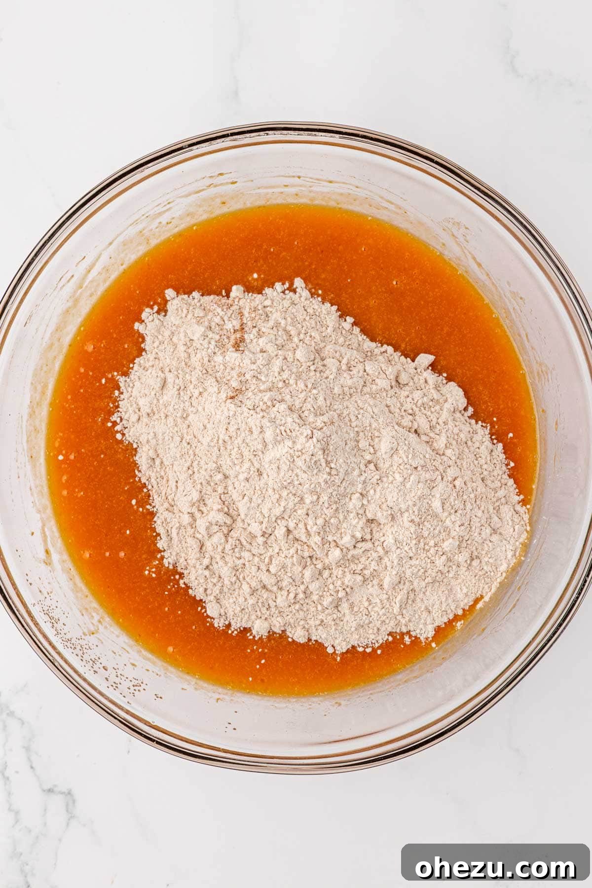dry ingredients being poured into the bowl of wet ingredients for pumpkin bread