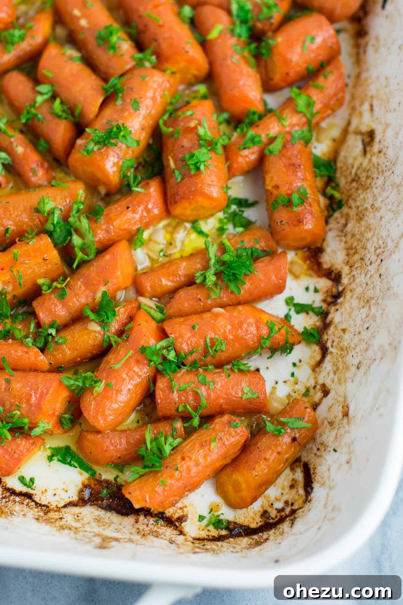 Close-up of garlic butter roasted carrots, highlighting the glistening buttery coating and minced garlic pieces.