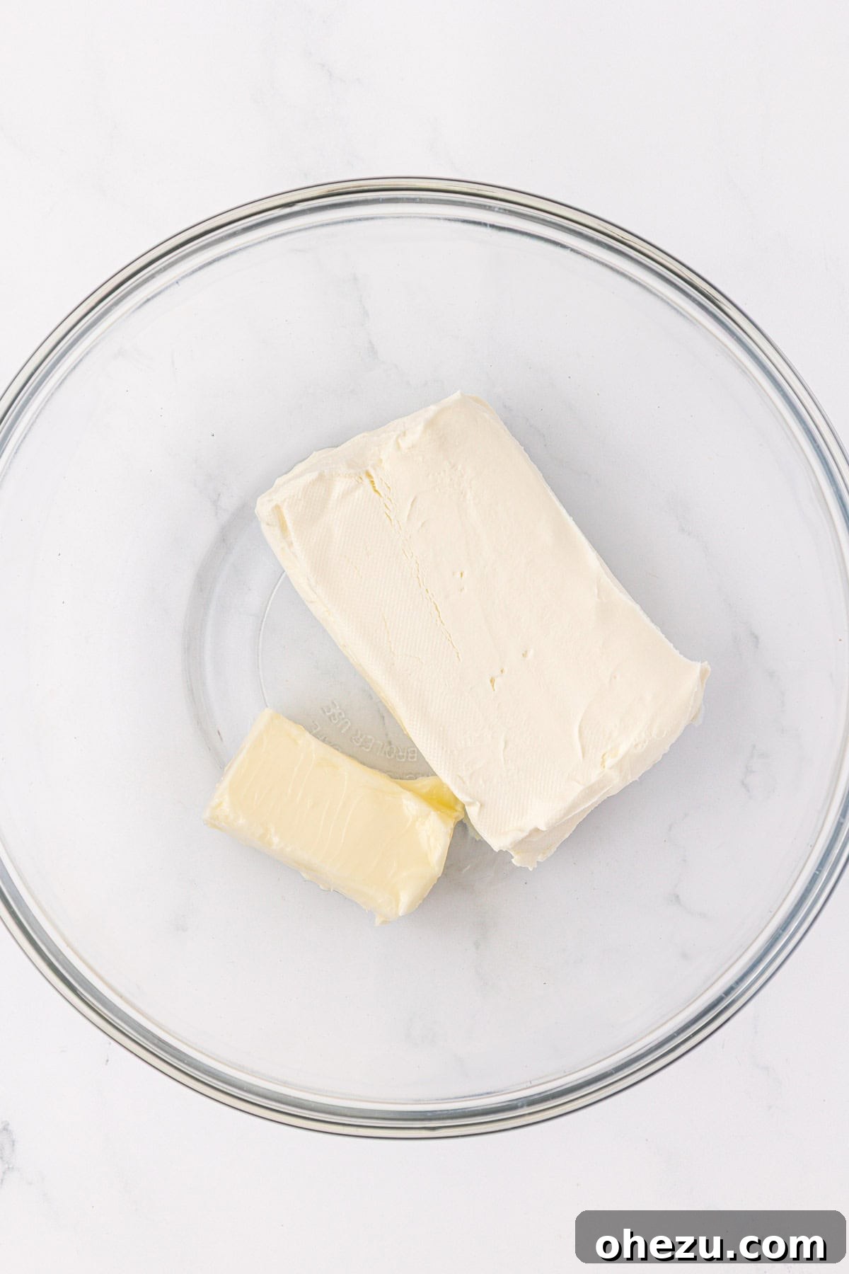 Softened butter and cream cheese in a mixing bowl, essential for smooth frosting