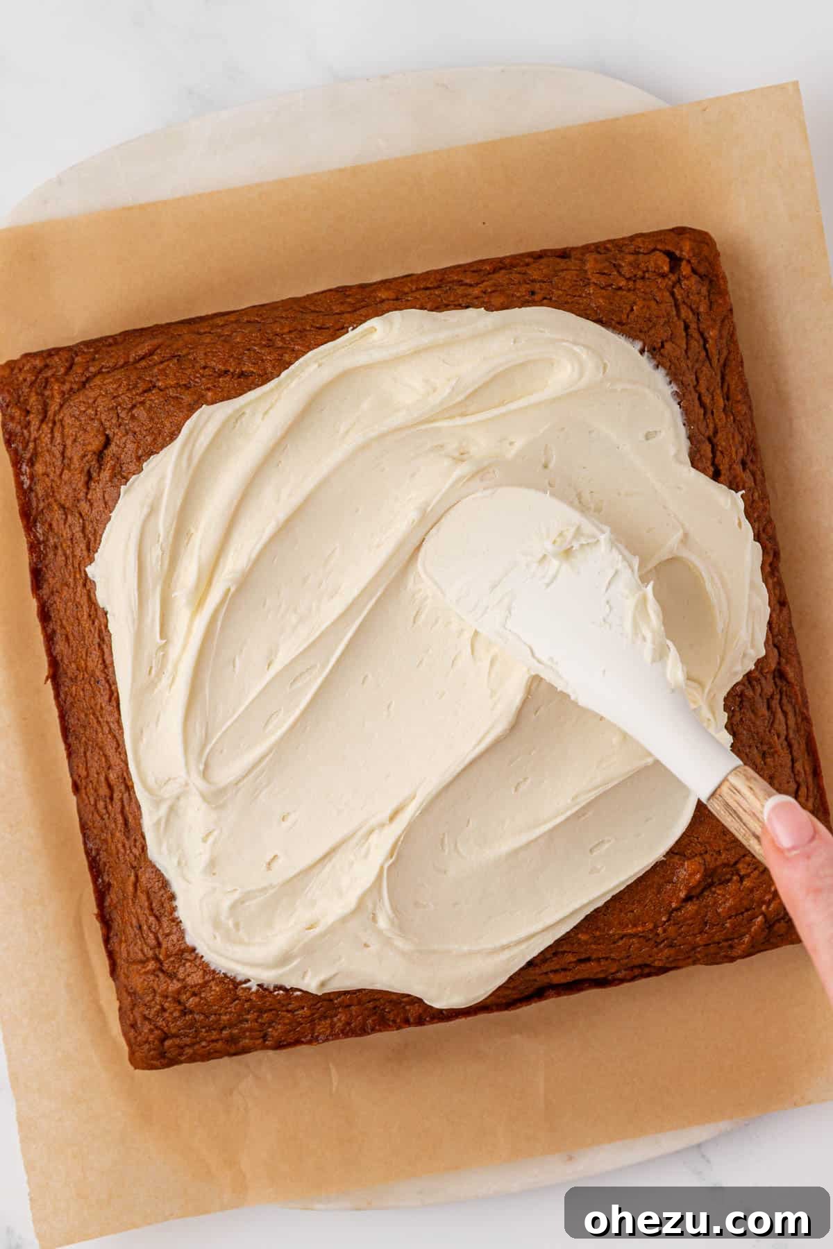 Expertly spreading smooth cream cheese frosting onto the cooled pumpkin cake