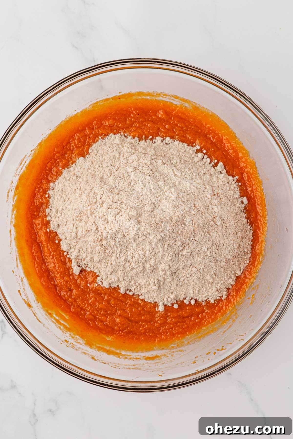 Adding dry ingredients gradually to the wet pumpkin cake batter