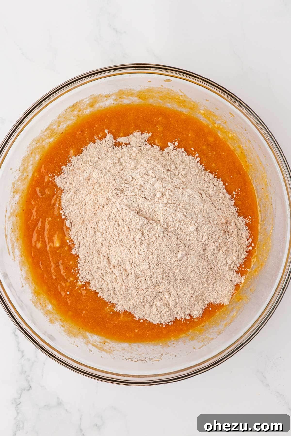 Adding dry flour mixture into the bowl of wet ingredients for muffins