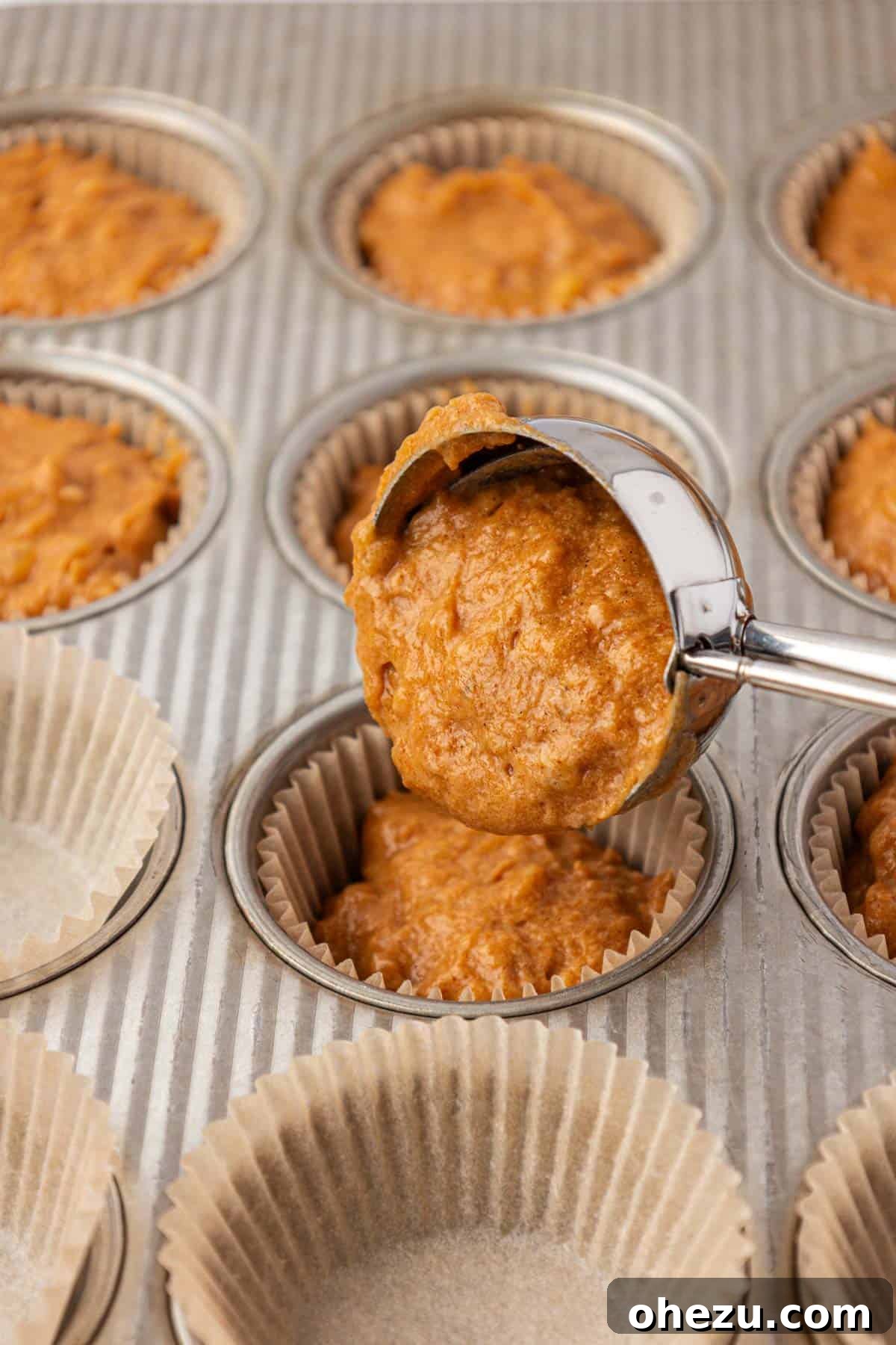 Scooping pumpkin banana muffin batter into lined muffin cups