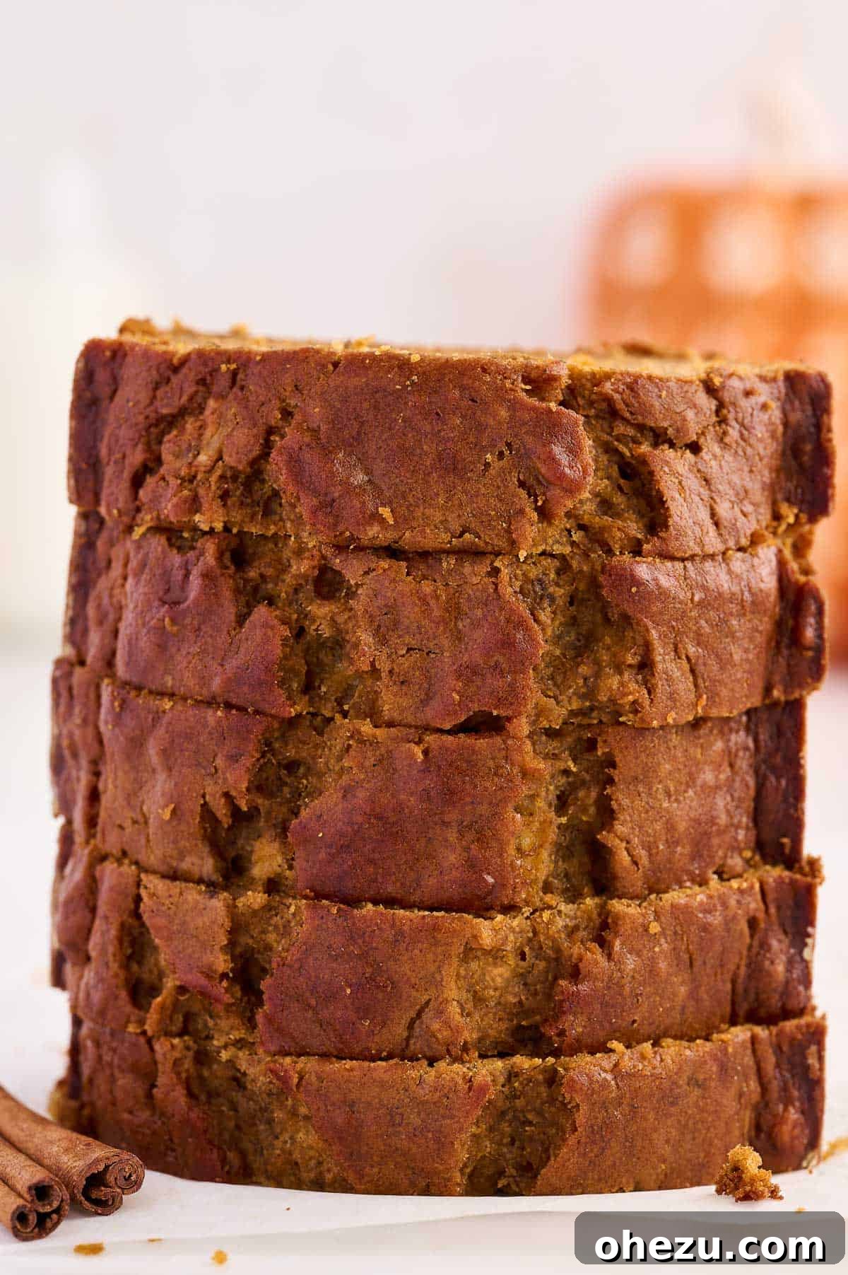 A neatly stacked pile of pumpkin banana bread slices on a plate, indicating readiness for storage or serving