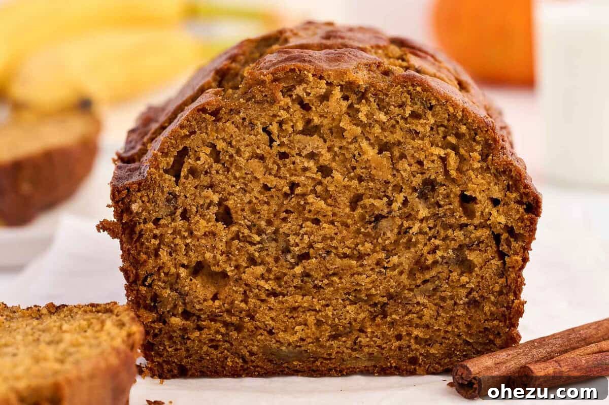 A full, rustic loaf of homemade pumpkin banana bread resting on a wooden cutting board, ready to be sliced