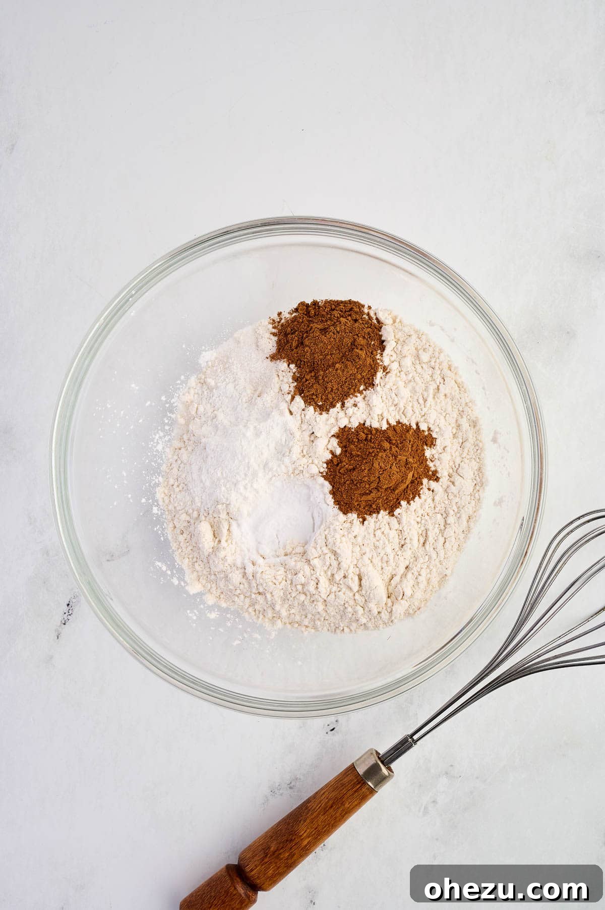 Measured dry ingredients including flour, spices, and leavening agents, settled in a large mixing bowl