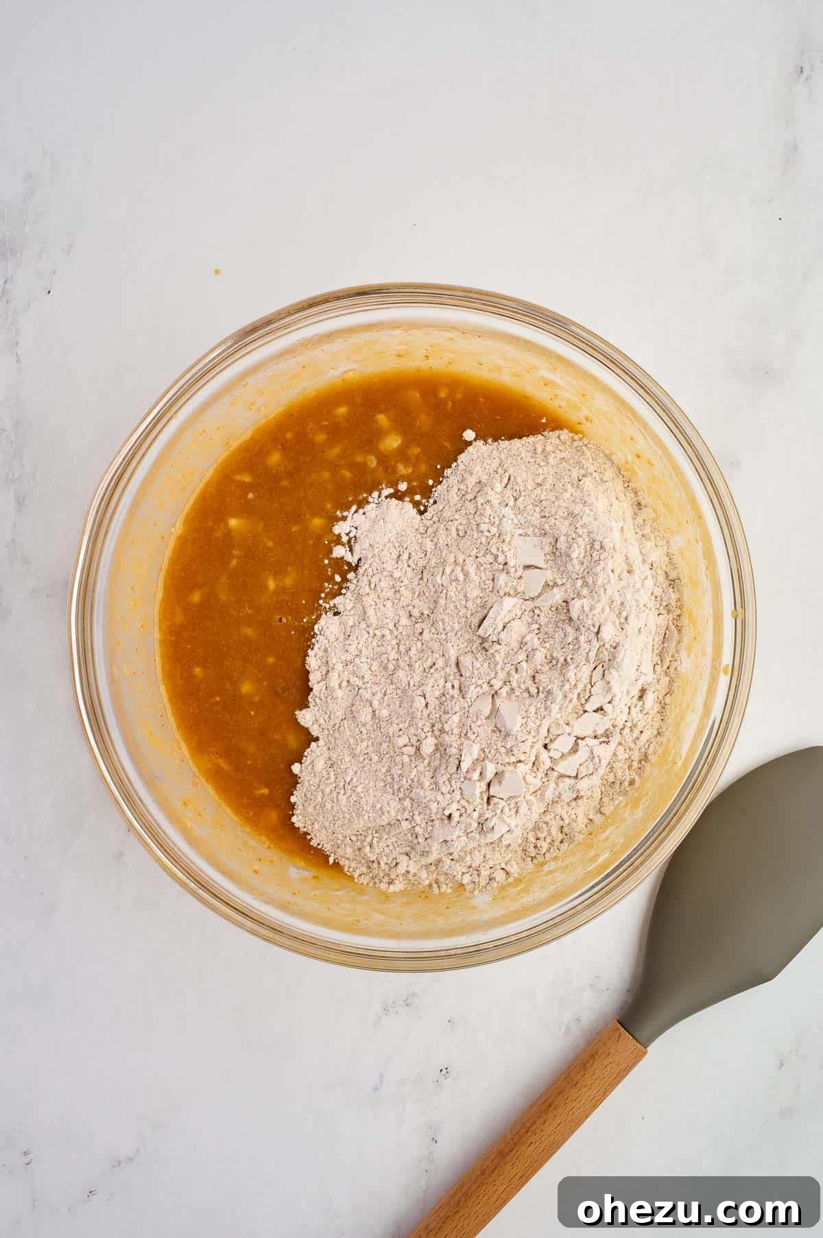 Dry ingredients being carefully and gently folded into the wet ingredients using a broad rubber spatula