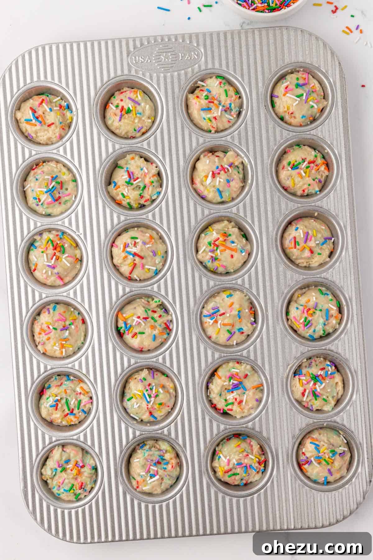 Mini muffin tin with additional sprinkles on top of the batter before baking