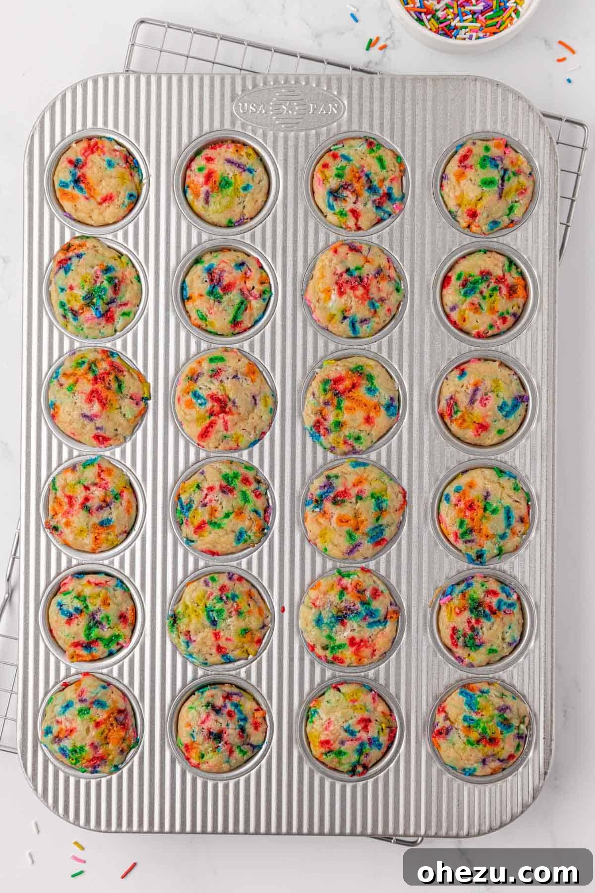 Freshly baked birthday cake mini muffins cooling in the tin
