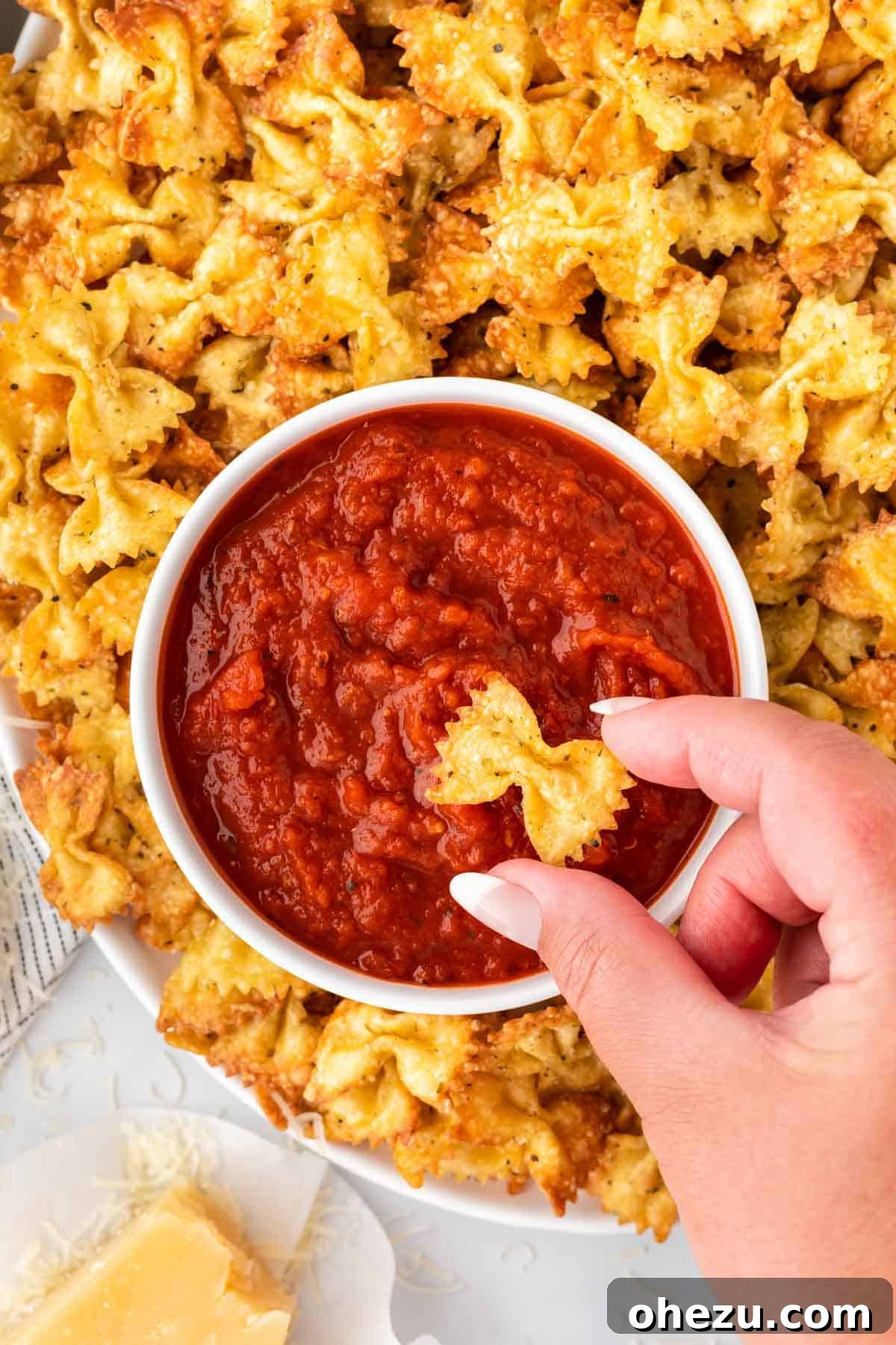 Crispy golden air fryer pasta chips piled high next to a small bowl of marinara sauce for dipping.
