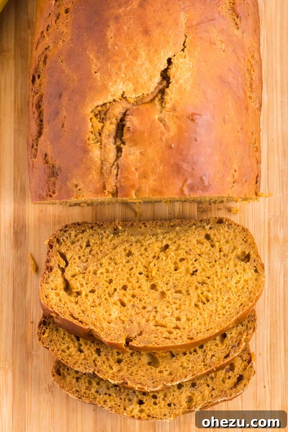 A freshly baked loaf of healthy pumpkin banana bread being cut into slices, showcasing its moist texture and inviting aroma.