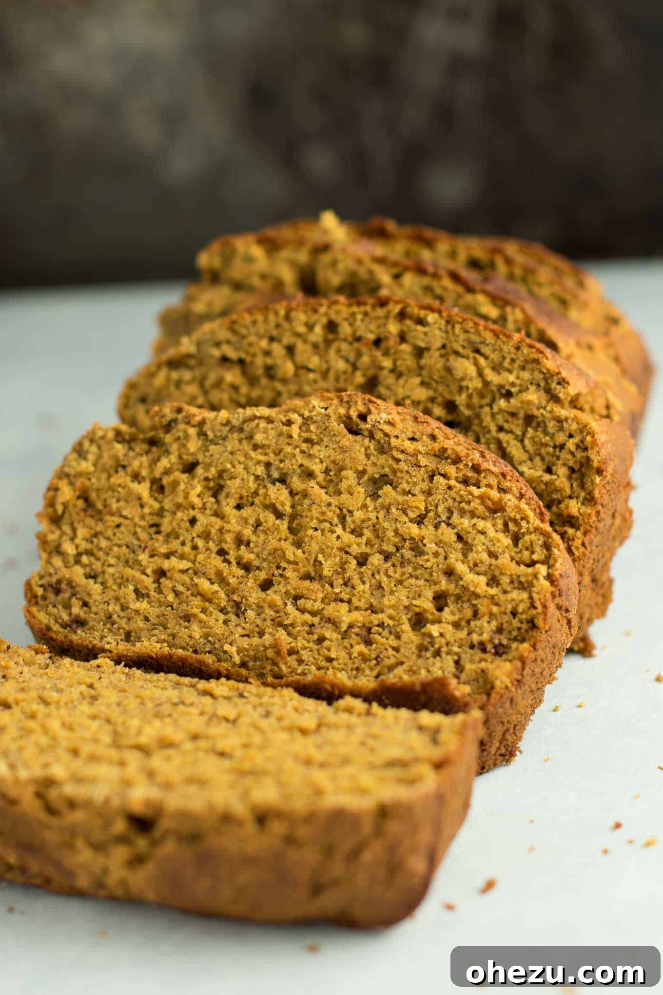 Close-up of three slices of pumpkin banana bread showcasing the moist interior texture, flecked with spices.