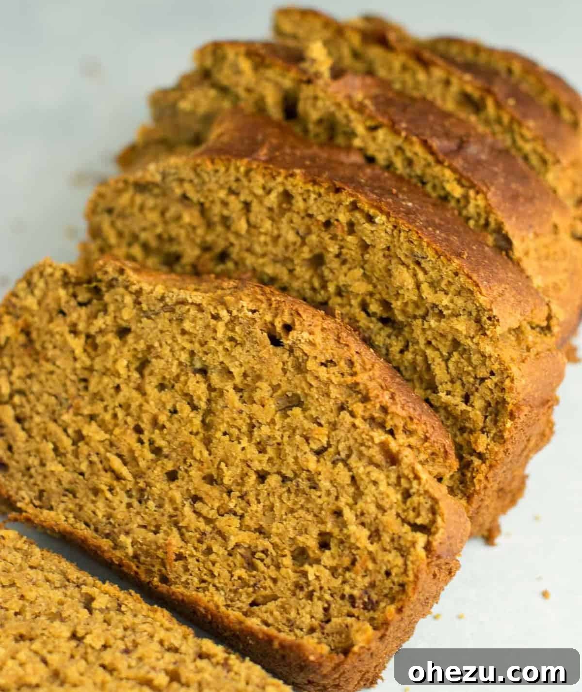 Several slices of healthy pumpkin bread artfully arranged, some resting on each other, showing their texture.