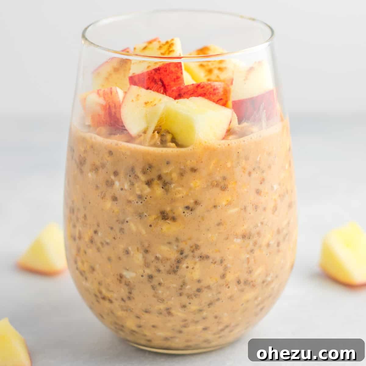 Ingredients for apple cinnamon overnight oats laid out: rolled oats, almond milk, chia seeds, vanilla, cinnamon, maple syrup, peanut butter, and chopped apples.