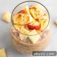 overnight oats in a glass topped with diced apples and cinnamon