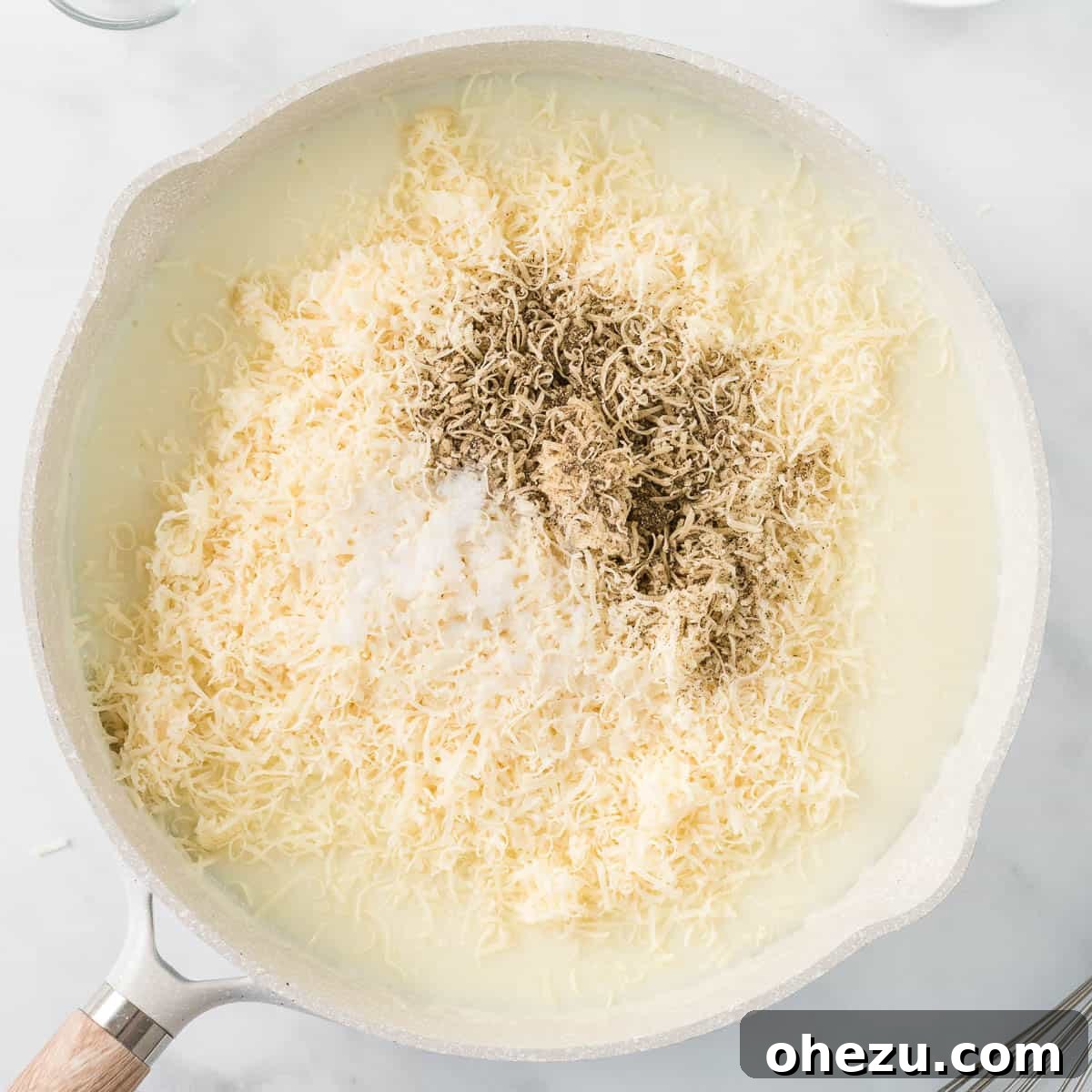 adding the cheese, salt, and pepper to the alfredo sauce