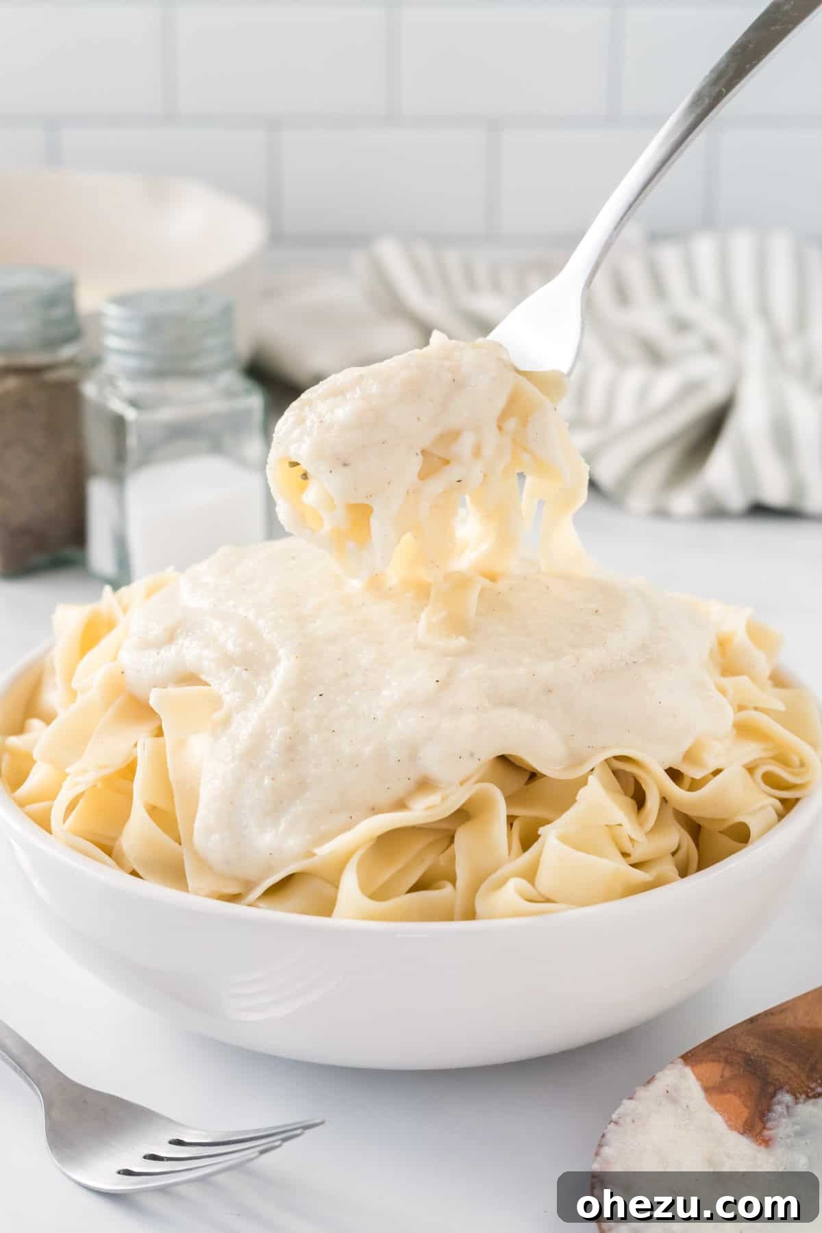 a fork taking a bite of fettuccini with Alfredo sauce