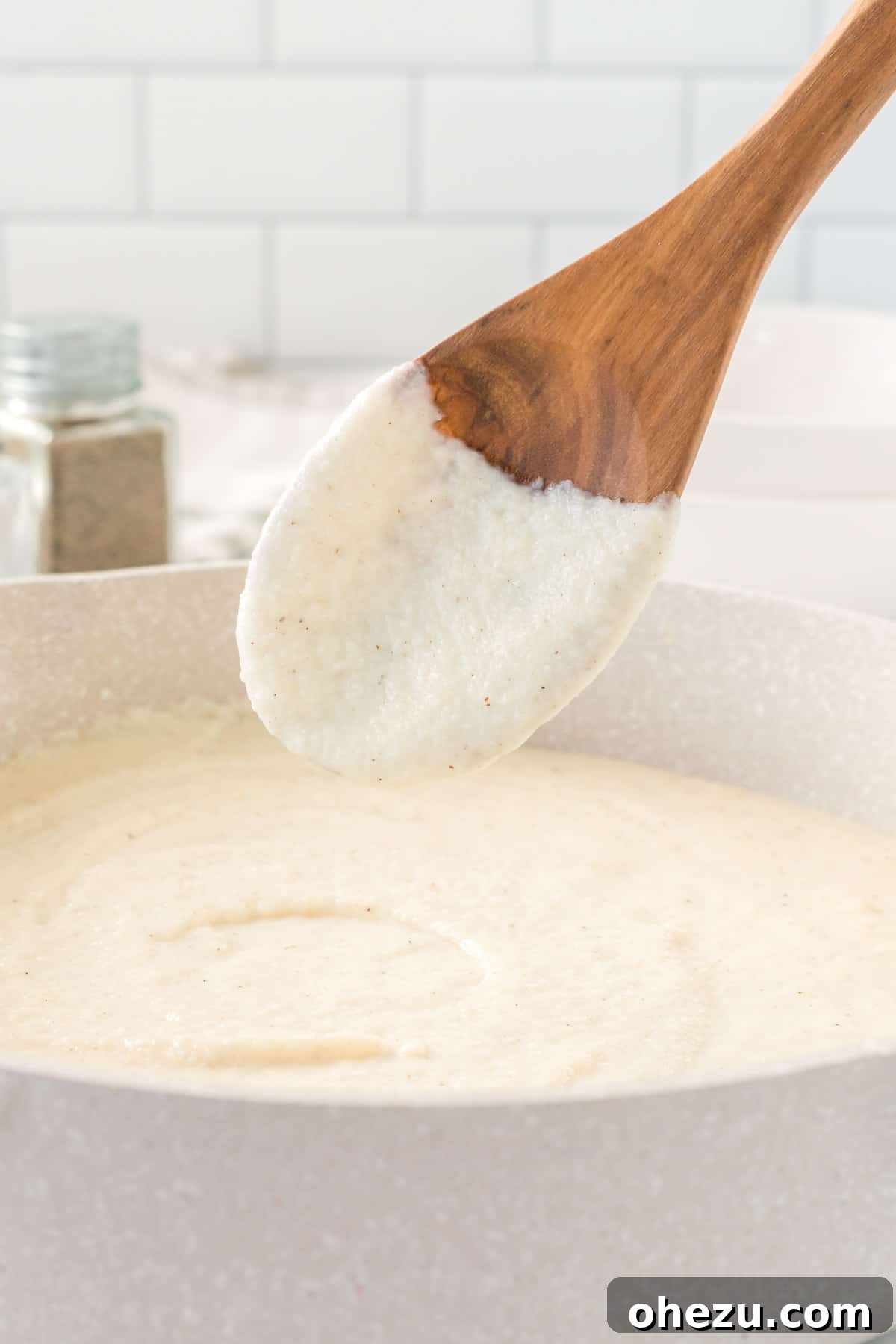 wooden spoon dipped in cauliflower alfredo sauce