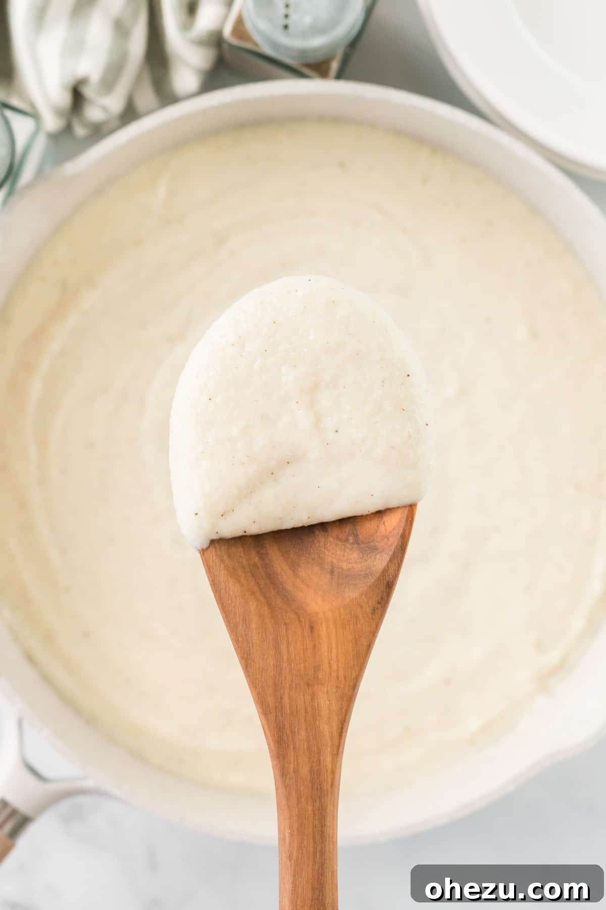 wooden spoon dipped in cauliflower alfredo sauce