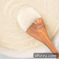 wooden spoon dipped in cauliflower alfredo sauce