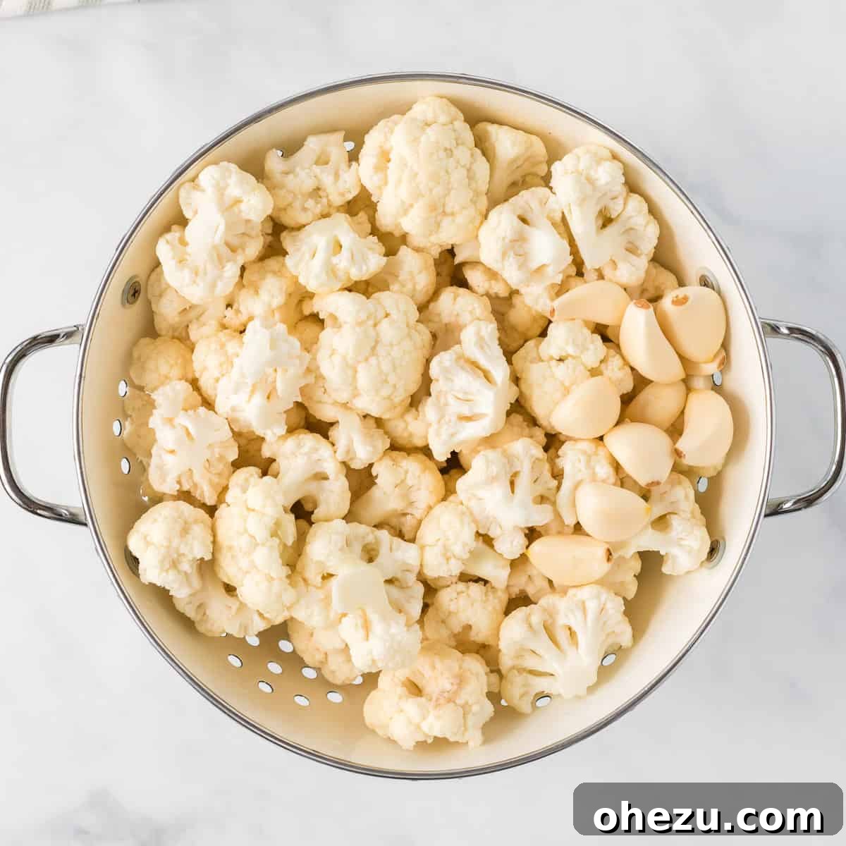 cauliflower florets and garlic cloves in a strainer