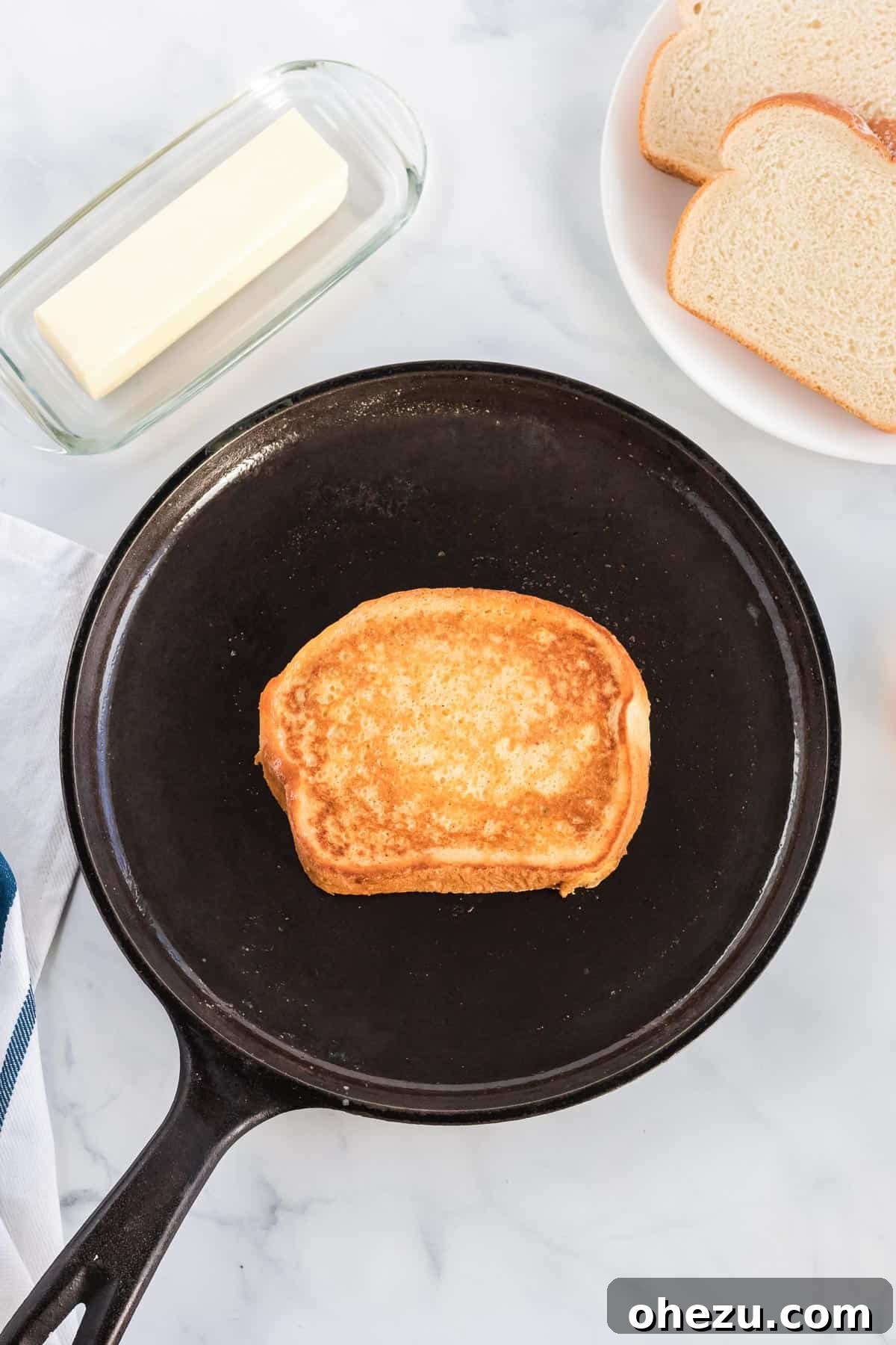 Festive Eggnog French Toast 5 Several slices of eggnog French toast cooking in a hot cast iron skillet, turning golden brown and sizzling gently, indicating perfect doneness.