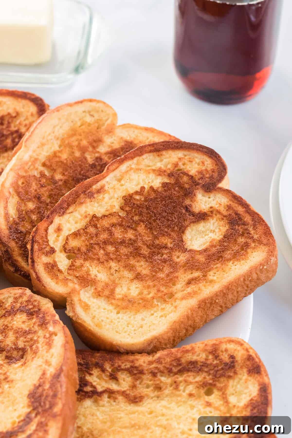 Festive Eggnog French Toast 6 A beautiful stack of freshly cooked eggnog French toast slices on a clean white plate, ready for toppings.