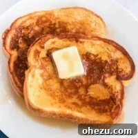 Close-up of a stack of Eggnog French Toast with butter and syrup