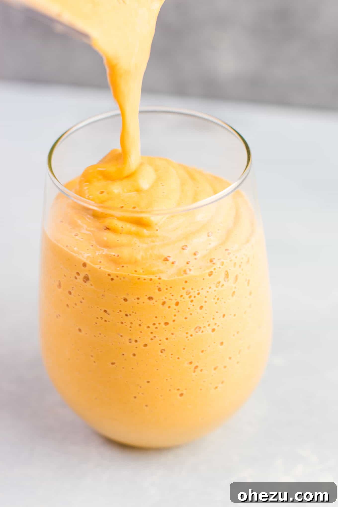 A glass filled with a creamy pumpkin pie smoothie, showing the thick and rich texture, ready for toppings.