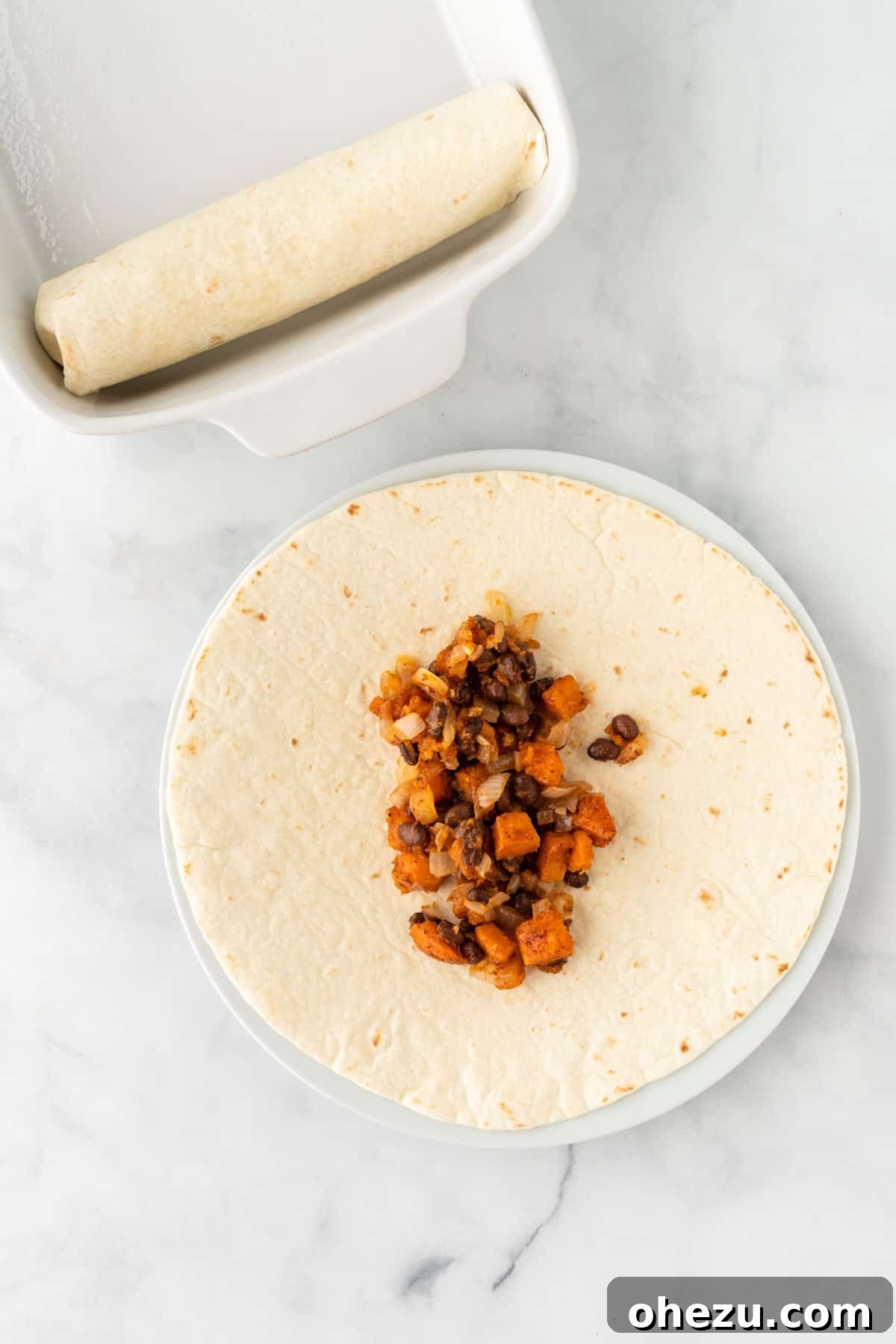 A soft taco shell being filled with a generous amount of the sweet potato and black bean mixture.