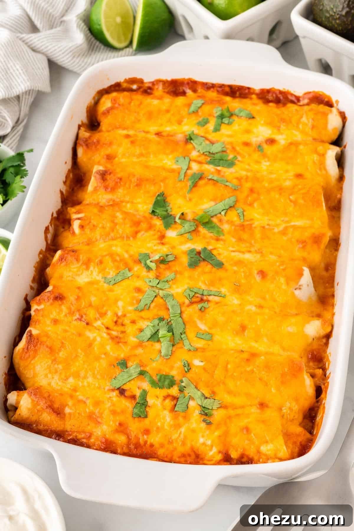 Close-up shot of the sweet potato black bean enchiladas in the baking dish, showing the bubbly cheese and rich sauce.