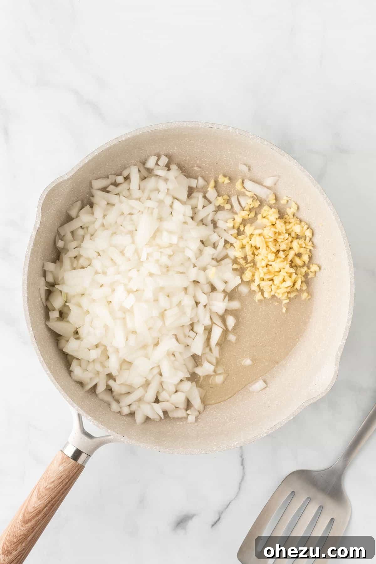 Diced onion and minced garlic sizzling in a hot skillet with olive oil.