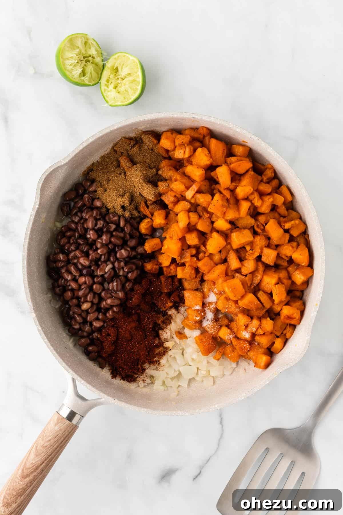 Adding roasted sweet potatoes, drained black beans, and a blend of spices to the skillet with the sautéed onions and garlic.