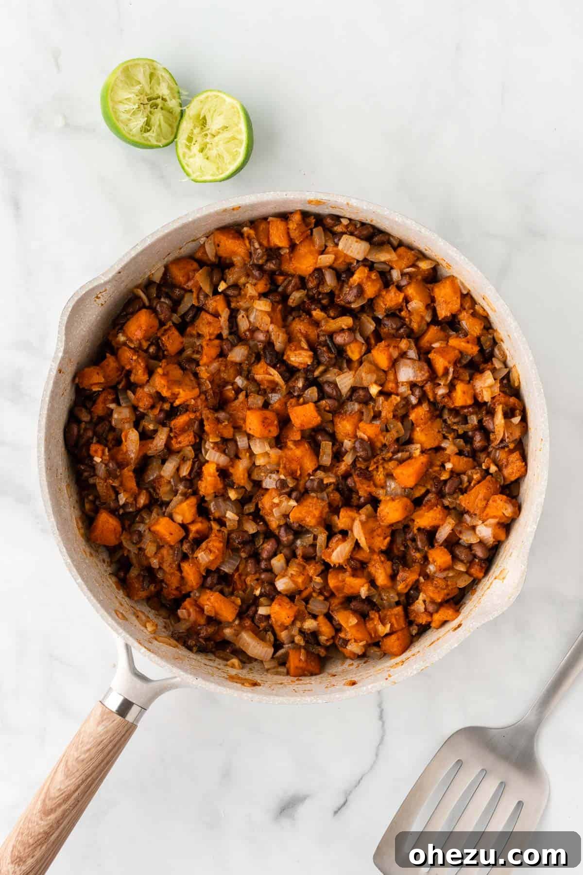The fully mixed sweet potato and black bean enchilada filling in a skillet, bursting with color and flavor.