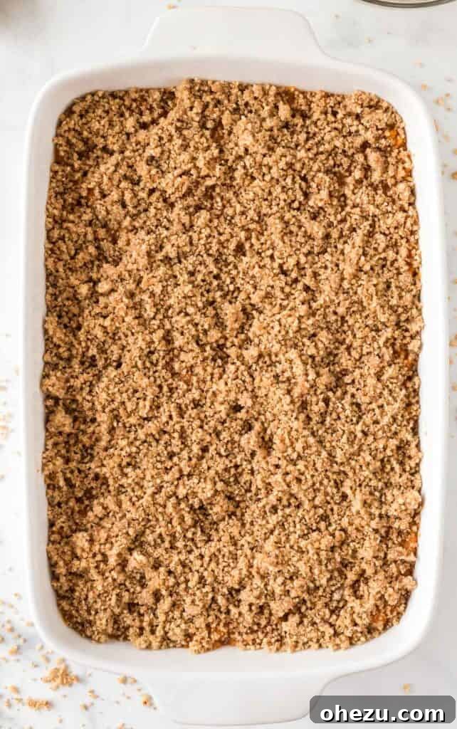 Golden Gluten-Free Sweet Potato Bake 12 Pecan topping being sprinkled evenly over the sweet potato filling in the casserole dish