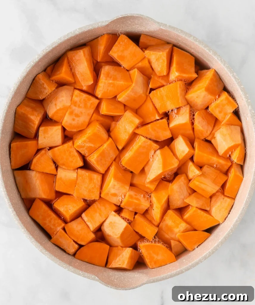 Golden Gluten-Free Sweet Potato Bake 5 Sweet potato chunks boiling in a pot of water on the stove
