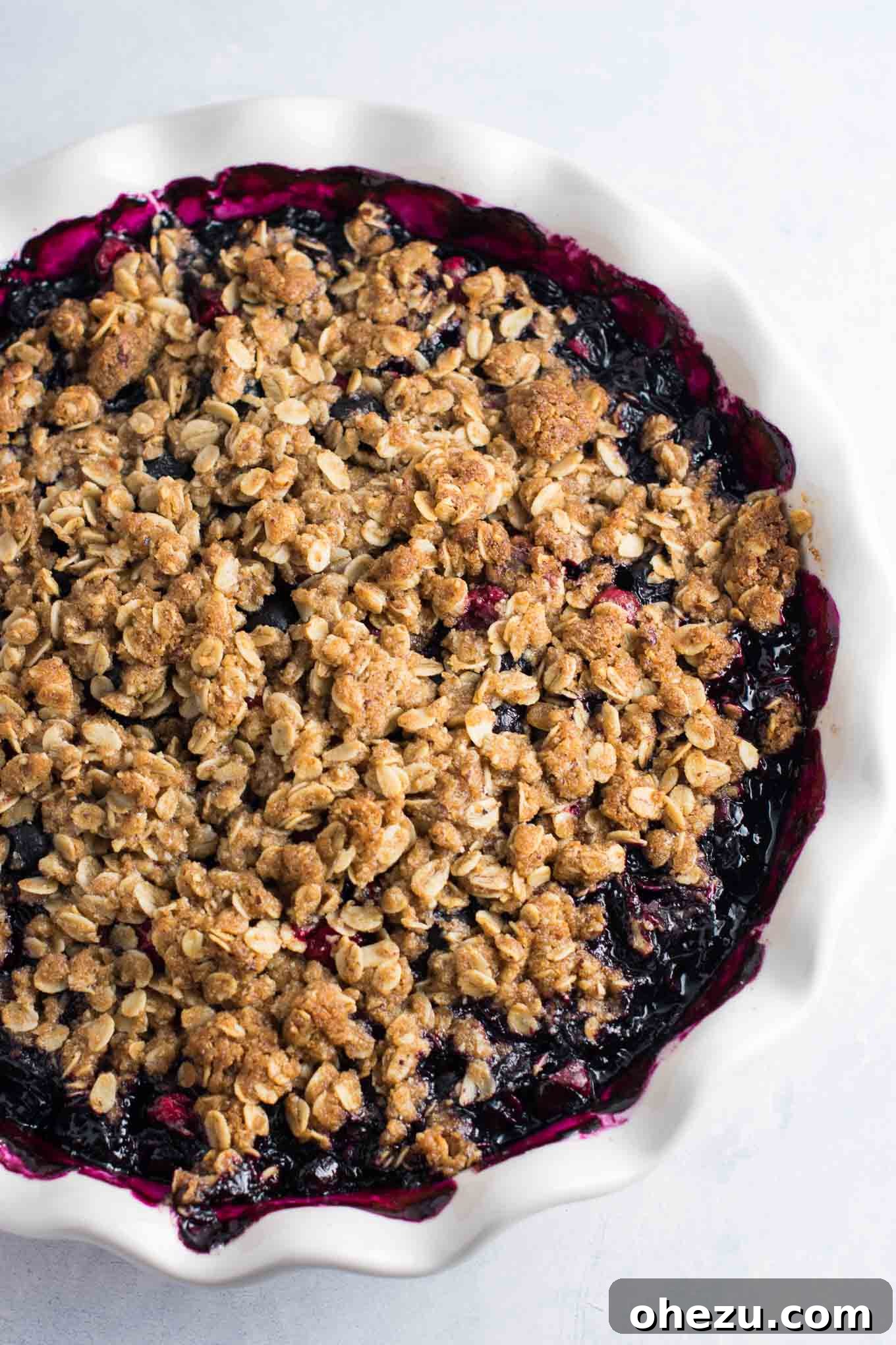 Cranberry blueberry crisp baking in a 9-inch pie dish, showing the fruit filling bubbling and the topping turning golden.