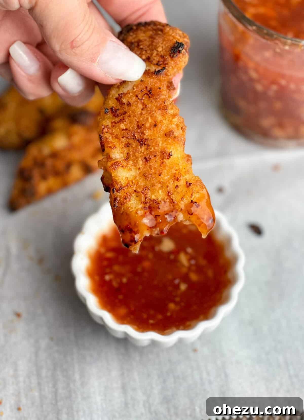 Close-up of the smooth, vibrant red sweet chili sauce in a bowl, garnished with fresh chili flakes