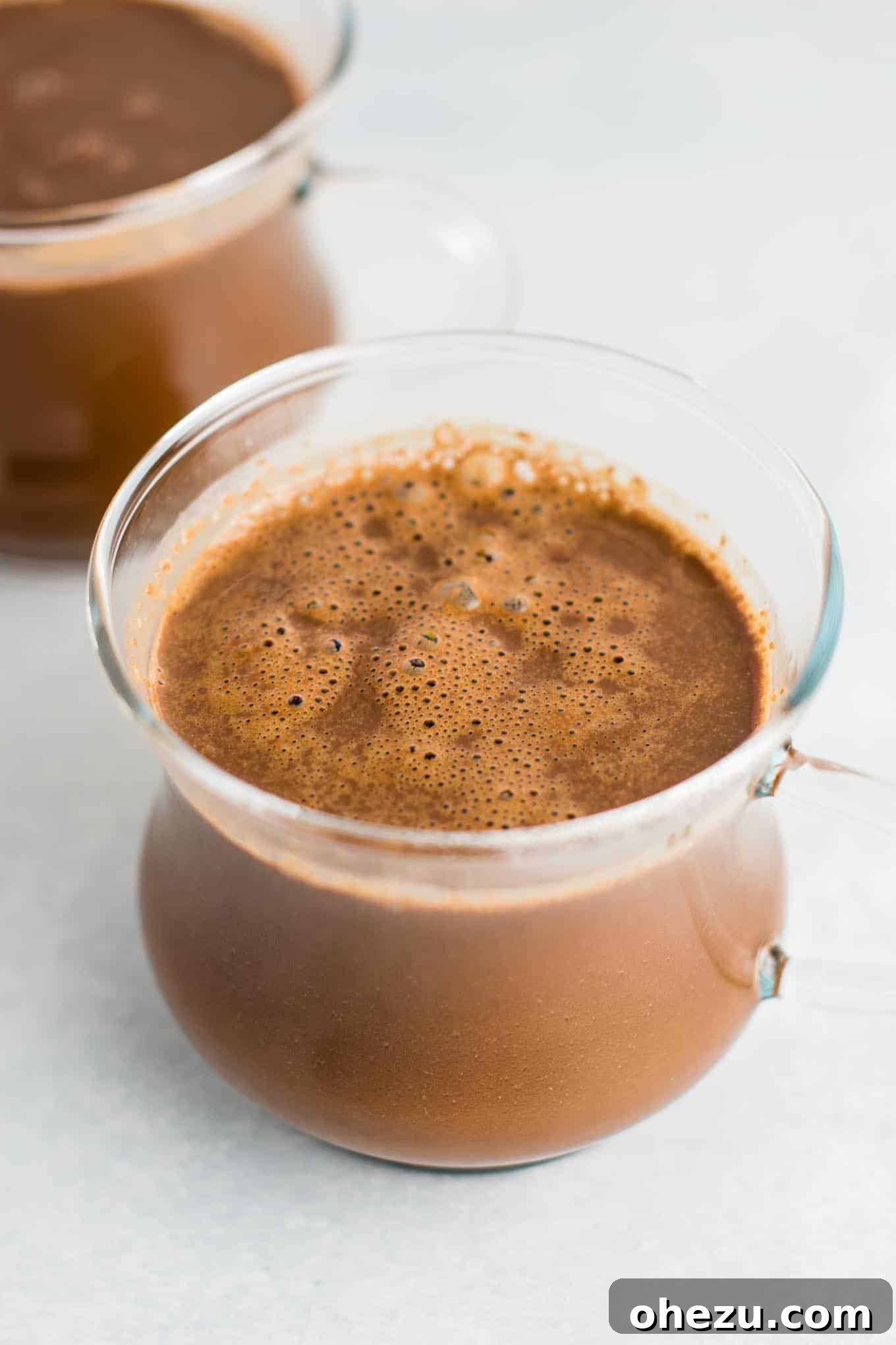Rich and creamy 4-ingredient vegan hot chocolate in a mug, topped with vegan whipped cream and chocolate shavings, perfect for a cozy winter day. Dairy-free, gluten-free, and easy to make.