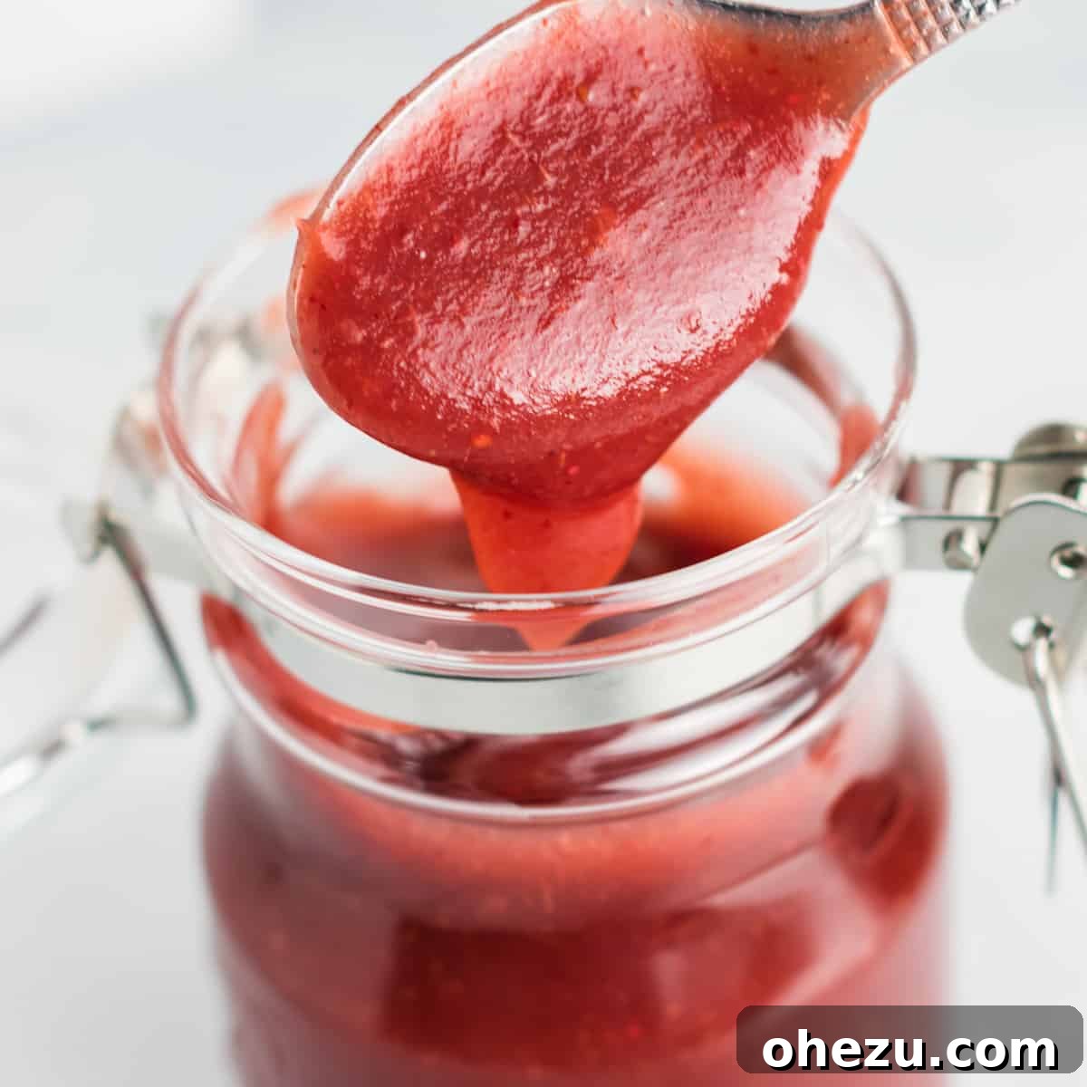 Sweet & Tangy Slow Cooker Cranberry Apple Butter 7 A spoonful of homemade cranberry apple butter being taken from a mason jar, highlighting its rich color and texture.