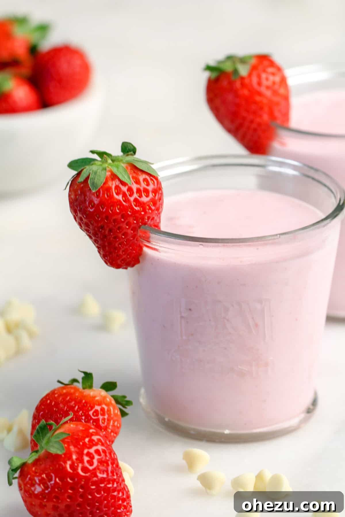 Strawberry White Chocolate Smoothie in a glass, with a single strawberry on the rim, ready to be enjoyed.